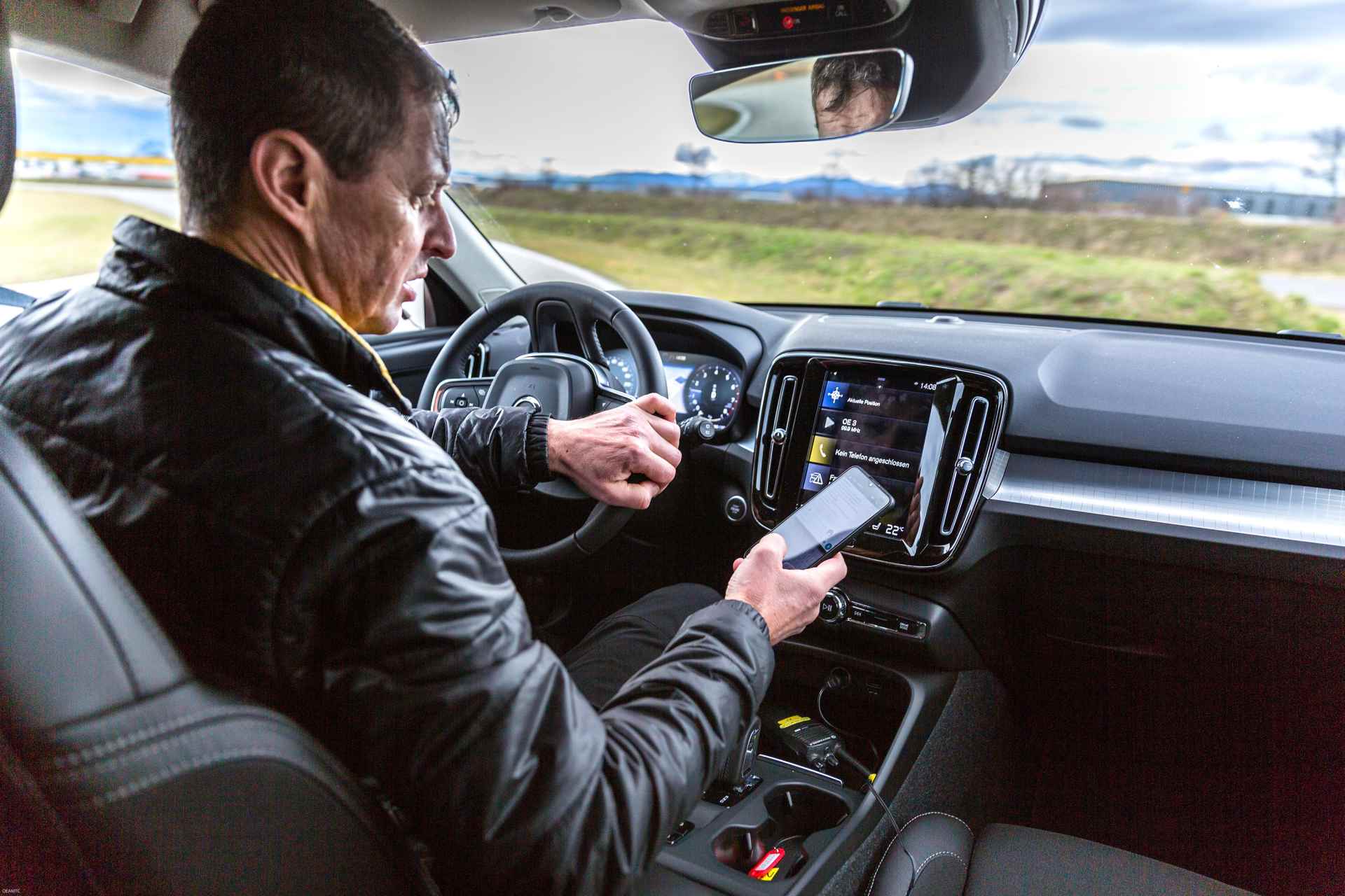 Autofahrer liest Nachricht auf Smartphone