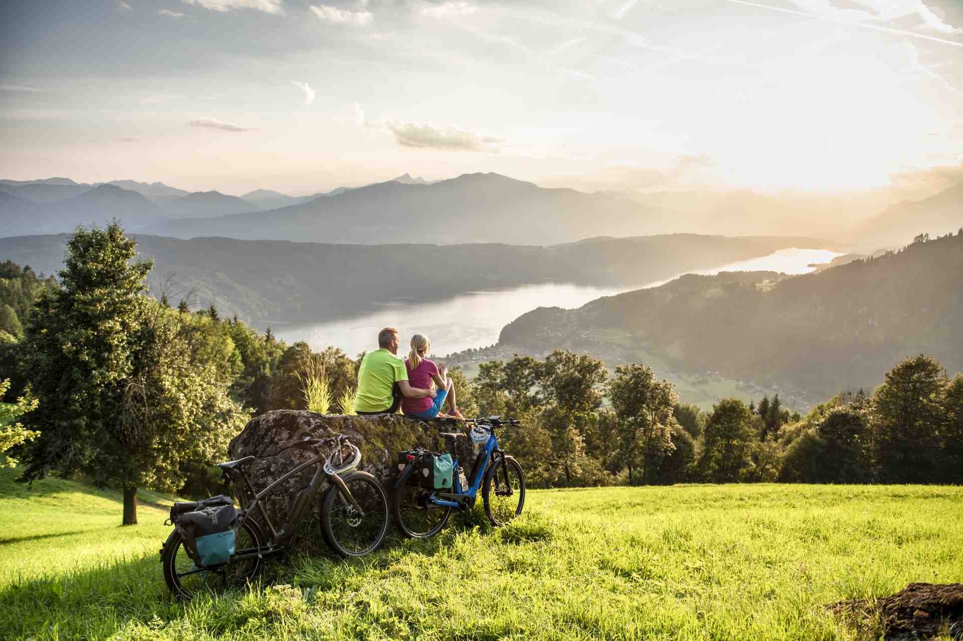 Fahrradfahrer blicken auf den Millstätter See bei Sonnenuntergang