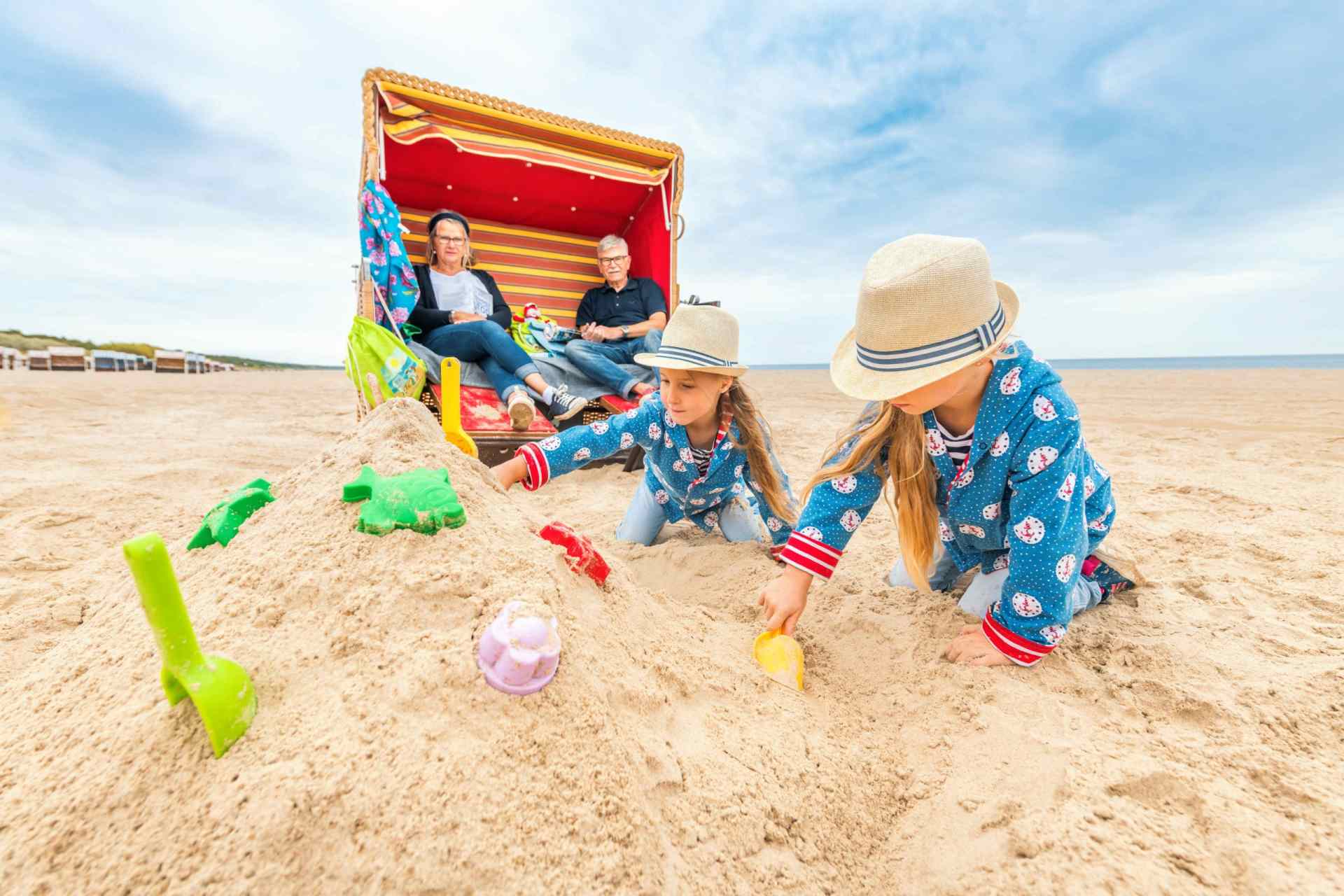 Kinder bauen Sandburgen vor einem Strandkorb in Trassenheide