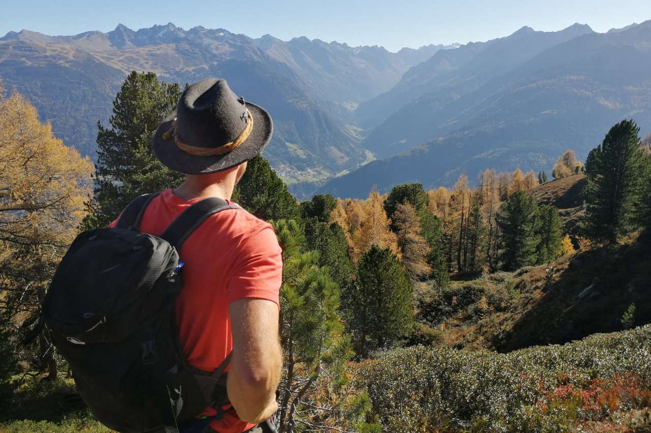 Wanderer blickt bei Wenns ins herbstliche Pitztal