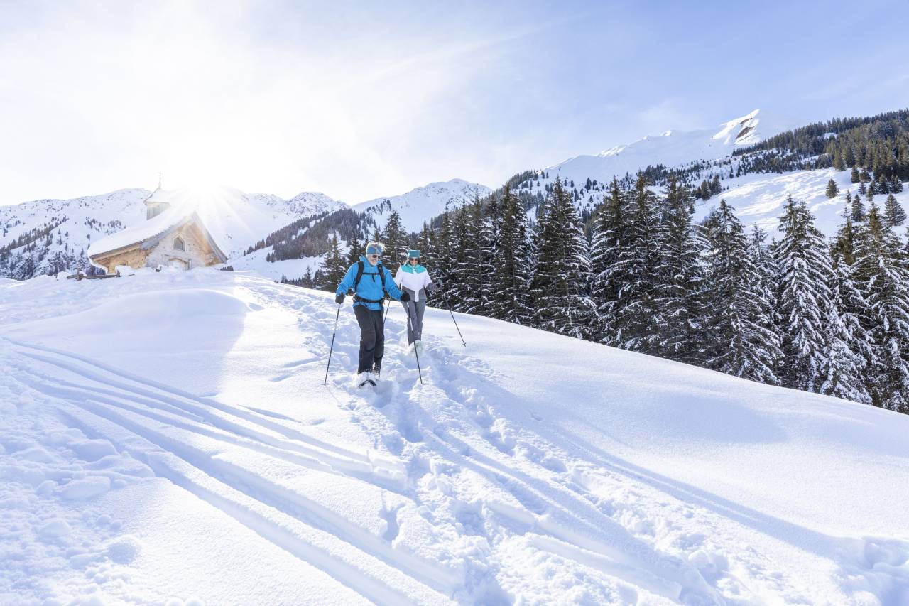 Winterwanderer auf der Schönangeralm mit der Zirbenkapelle