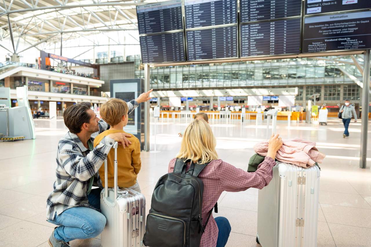 Familie vor Anzeigentafel Flughafen Hamburg