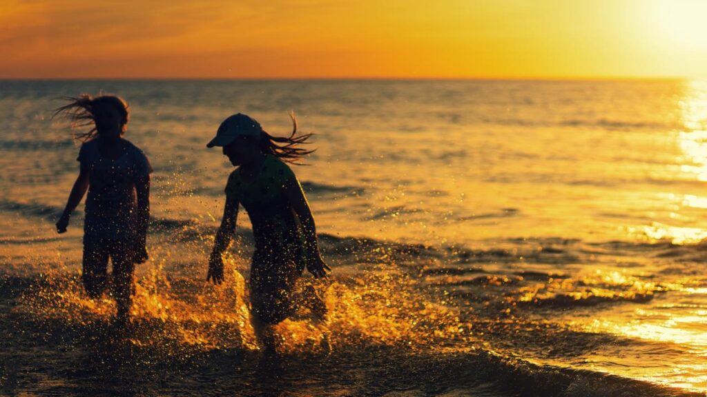 Mädchen spielen bei Sonnenuntergang am Strand