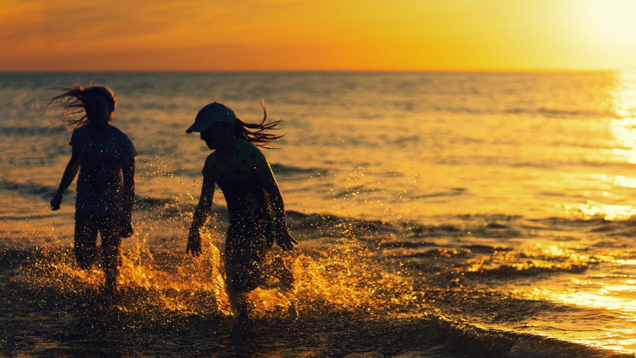 Mädchen spielen bei Sonnenuntergang am Strand