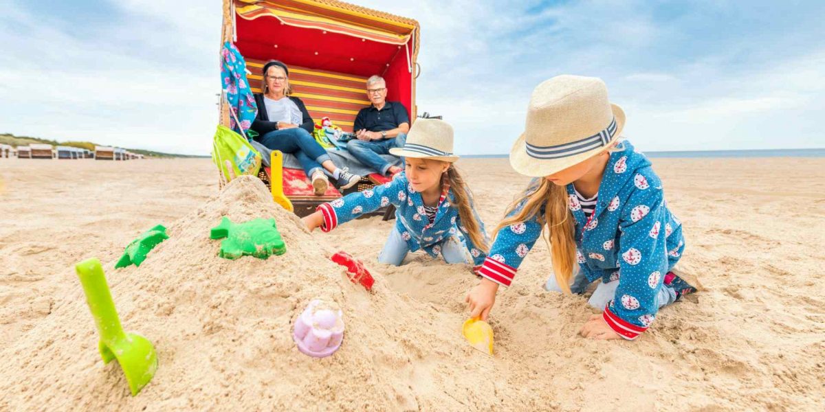 Kinder bauen Sandburgen vor einem Strandkorb in Trassenheide