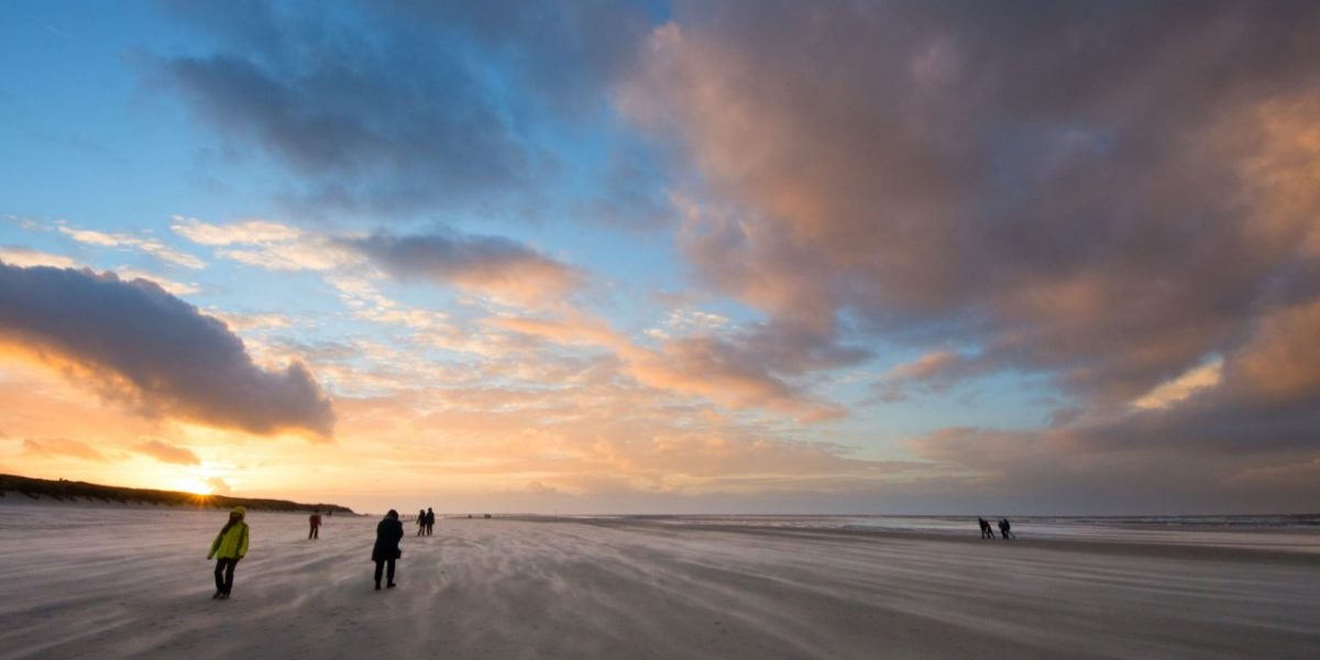 Spaziergänger im Herbstwind am Strand von Langeoog